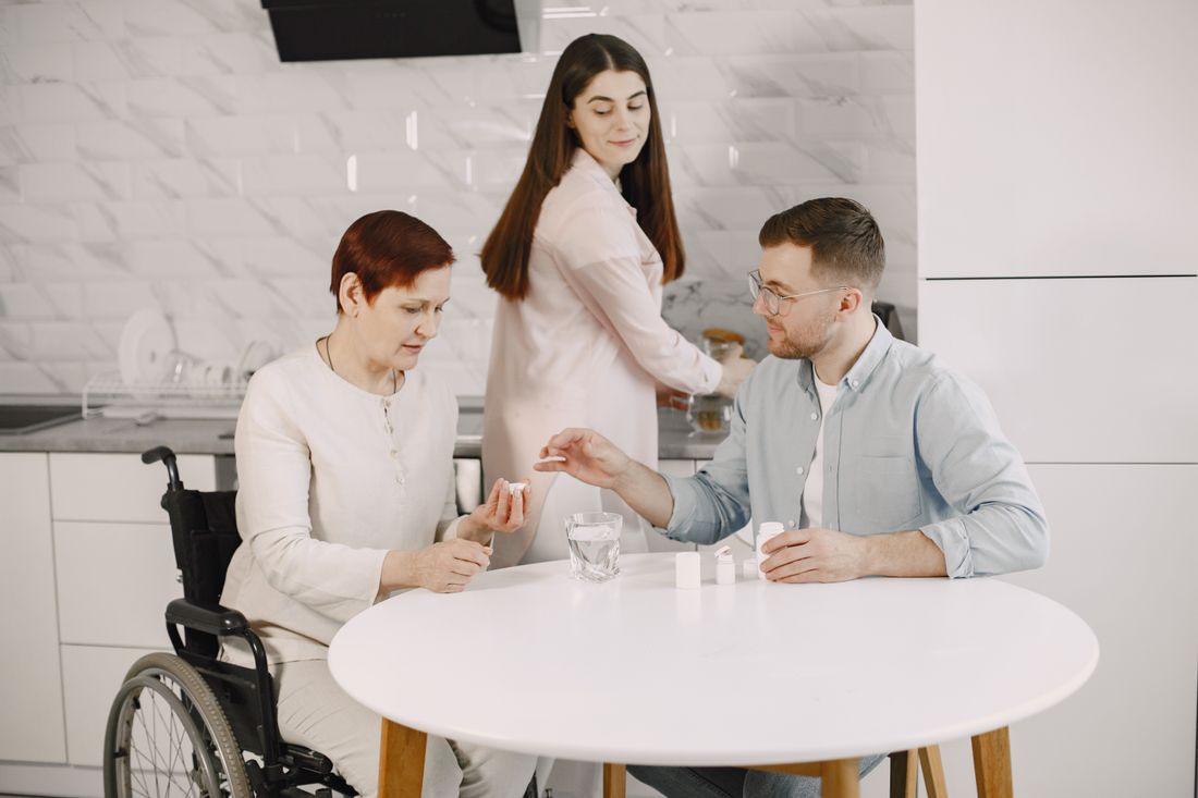 A family gathered around a table at home, including a relative who uses a wheelchair