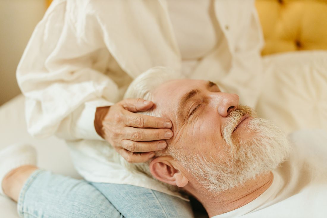 A caregiver supporting an elderly man walking outdoors